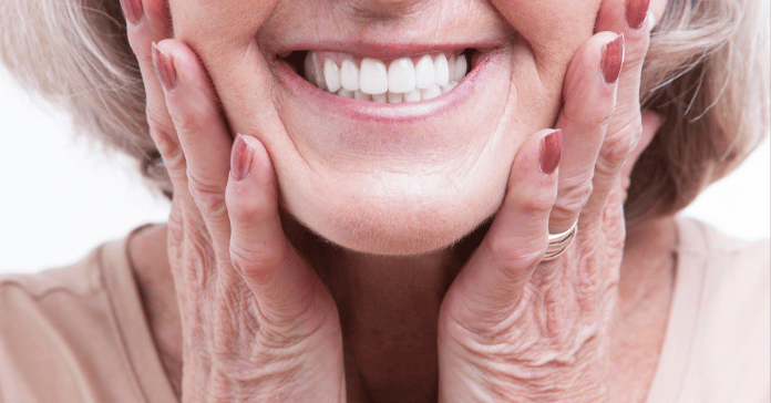 Smiling elderly woman showing clean dentures and healthy gums.