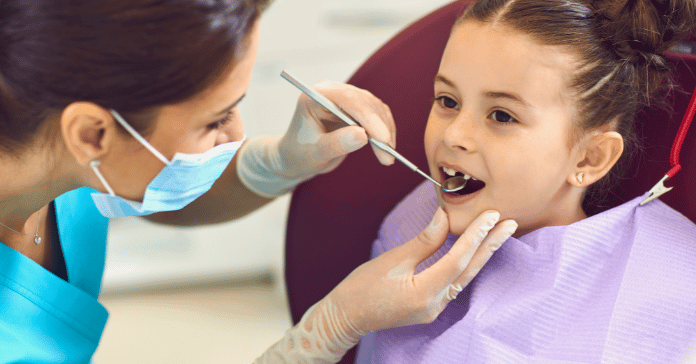 Pediatric dentist examining a child’s teeth during a dental checkup.