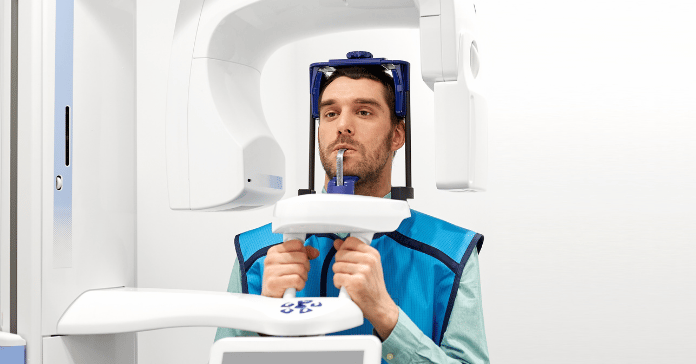 Patient undergoing a panoramic dental X-ray before dental implant placement.